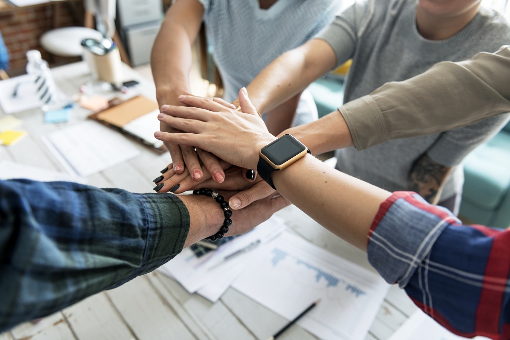 Kollegaer som stabler hendene opp på hverandre