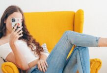 Smartphones Linked to Lower IQ, Norwegian Psychologist Claims woman in white tank top and blue denim jeans sitting on yellow sofa